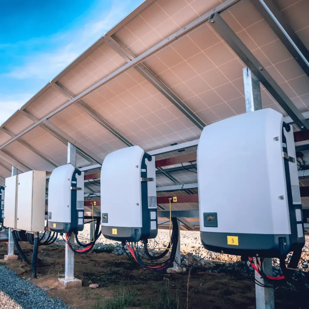 String inverters mounted under a row of solar panels