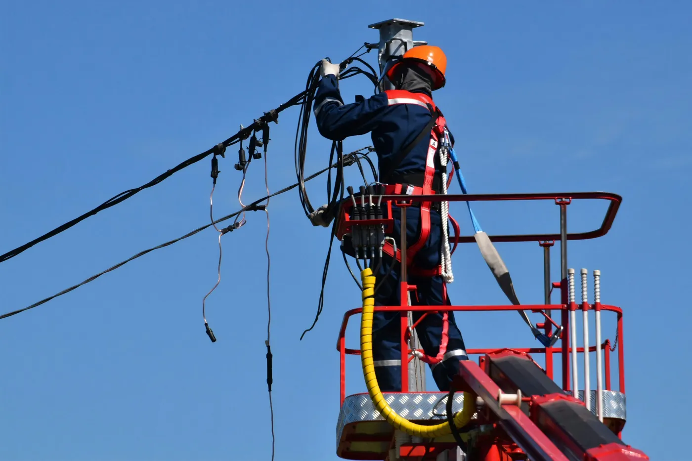 Lineworker in safety gear working on overhead power lines from a bucket lift